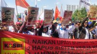 Foto: Ratusan buruh menggelar aksi di halaman Kantor Bupati Gresik sambil membawa spanduk tuntutan ketenagakerjaan.