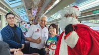 Foto: Direksi KAI Wisata dan KAI Commuter berbagi merchandise Natal kepada penumpang KA Panoramic Argo Wilis di Stasiun Surabaya Gubeng