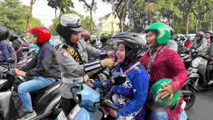 Foto: Polwan Satlantas Surabaya membagikan cokelat dan helm kepada pengendara perempuan di Hari Kartini