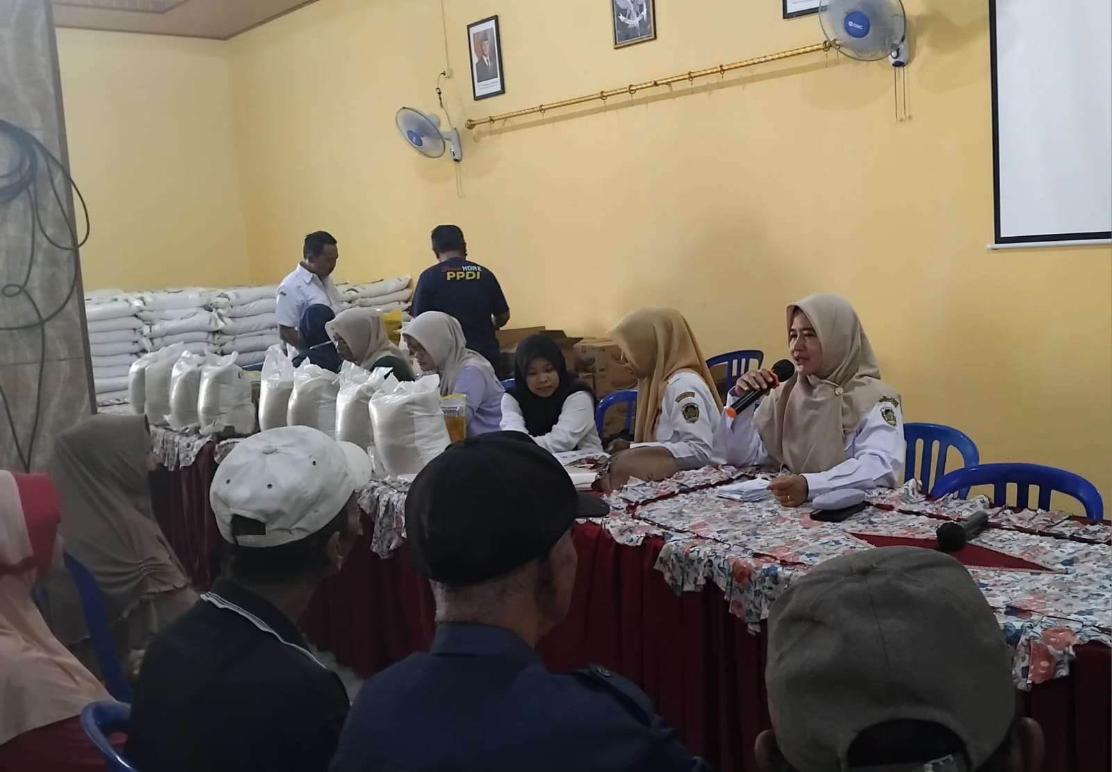Foto: Warga Desa Bongsopotro antre tertib menerima bantuan beras dan minyak goreng di balai desa Saradan Madiun