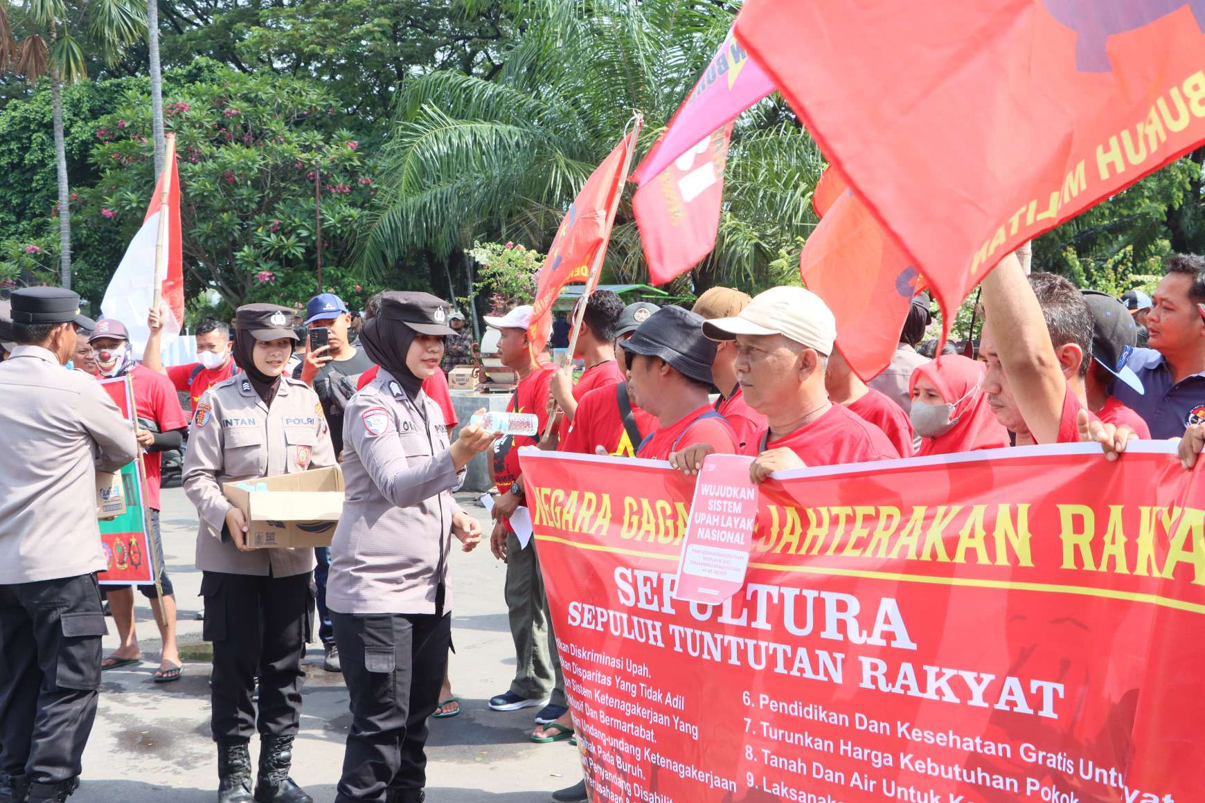 Foto: Polwan Polres Madiun Kota membagikan air mineral kepada peserta aksi May Day 2026 di Alun-Alun Kota Madiun