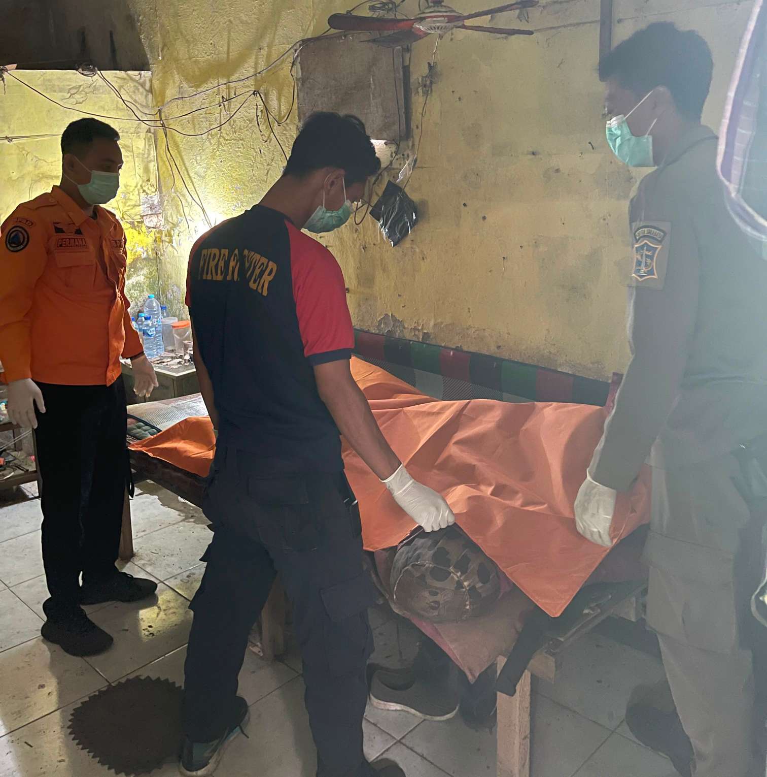 Foto: Petugas gabungan mengevakuasi jenazah seorang lansia yang ditemukan meninggal di rumah kos kawasan Sememi, Benowo, Surabaya.
